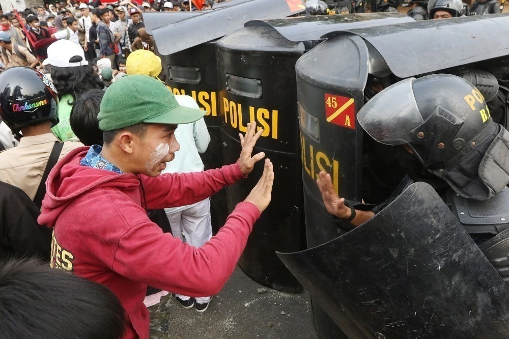 Polisi dan mahasiswa saling berhadapan saat aksi protes menentang revisi Undang-Undang Komisi Pemberantasan Korupsi (KPK) dan KUHP di luar kompleks DPR di Senayan, Jakarta, pada 25 September 2019. (The Jakarta Post/ Dhoni Setiawan)