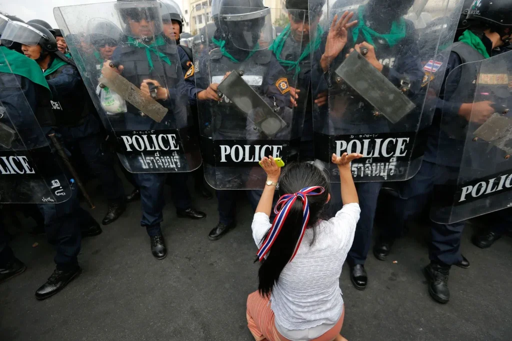 Seorang pengunjuk rasa anti-pemerintah mendorong barisan polisi saat bentrokan di dekat Gedung Pemerintah di Bangkok, pada 18 Februari 2014. Damir Sagolj—Reuters